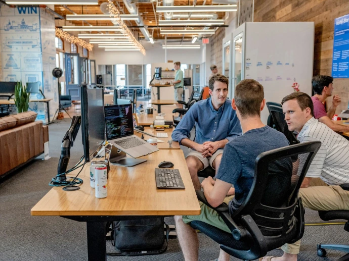 Office staff talking around a computer