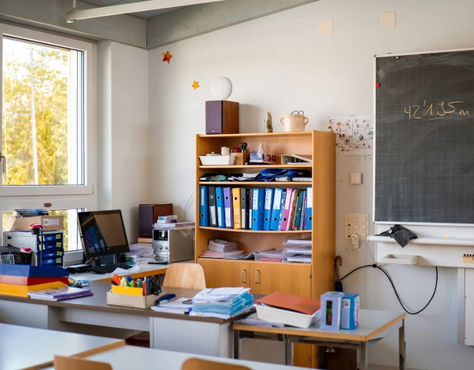 Classroom corner with desk, computer and filled storage shelves