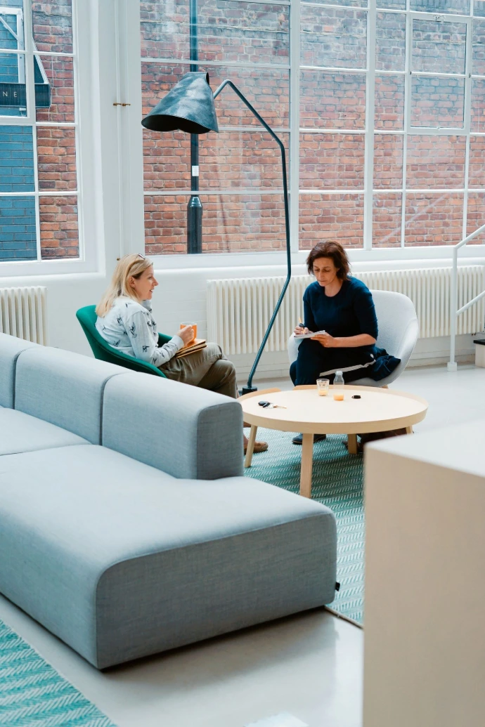 Two people sat in an office talking and taking notes