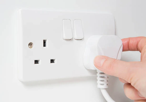 A plug being inserted into the wall socket